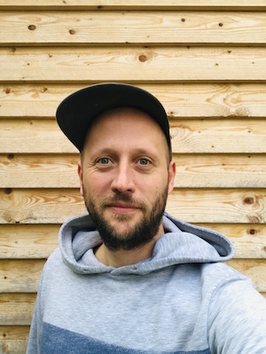 Das Bild zeigt Philippe vor einer Holzwand